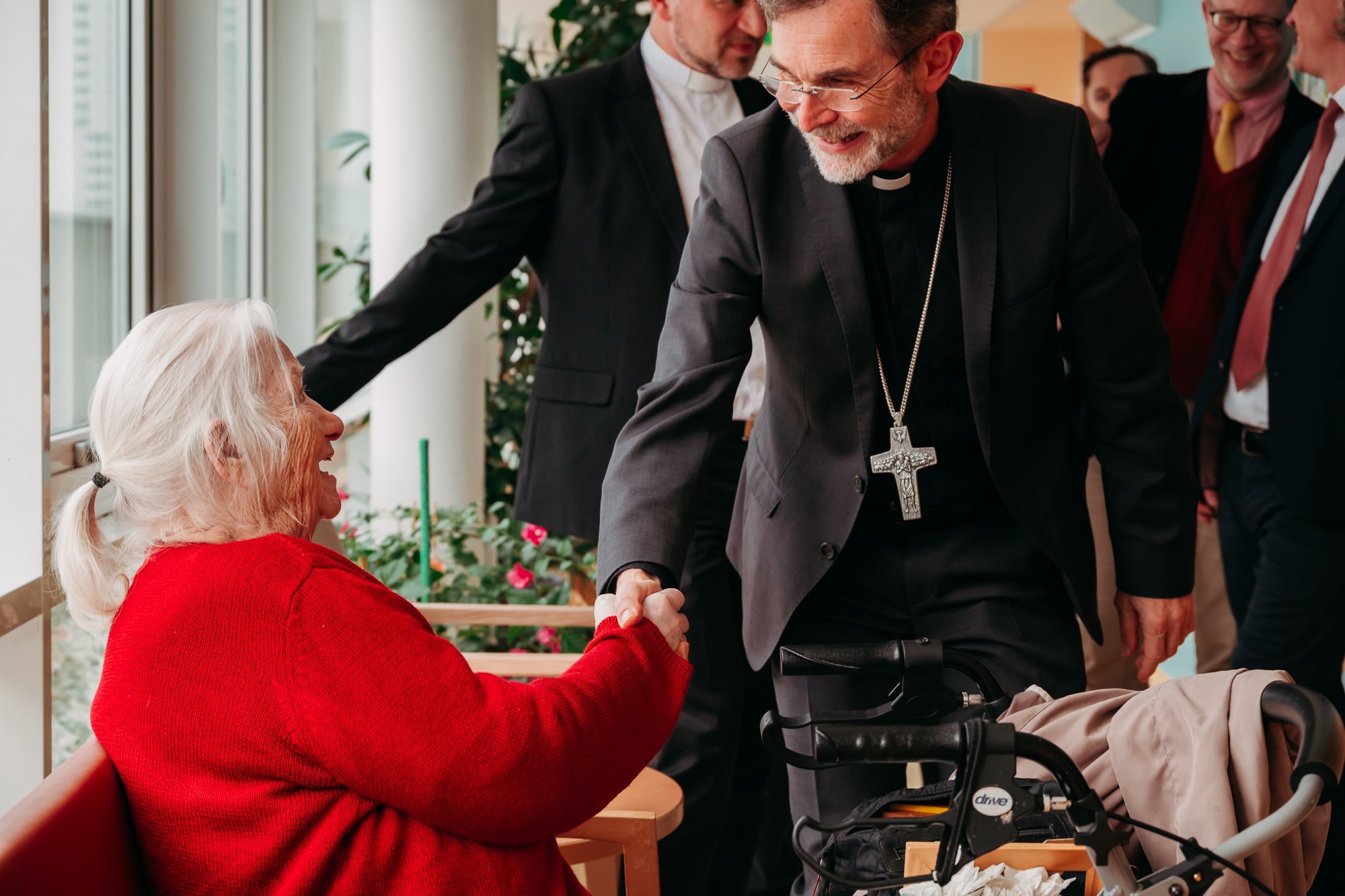 Bischof Grünwidl begrüßt eine ältere Bewohnerin des Kolpinghauses