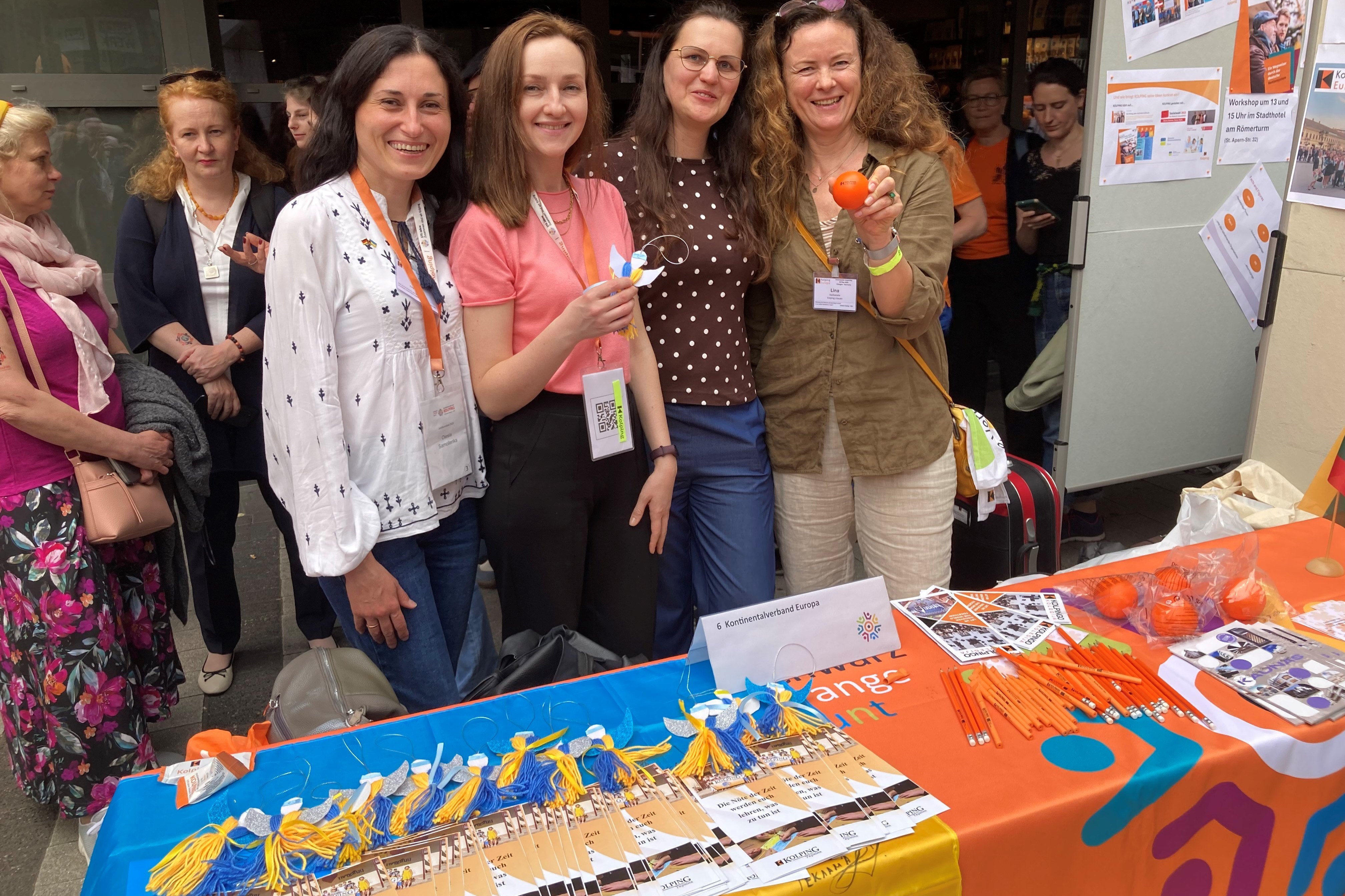 Vier fröhliche Frauen stehen an einem Verkaufstisch mit Werbematerial von Kolping Deutschland